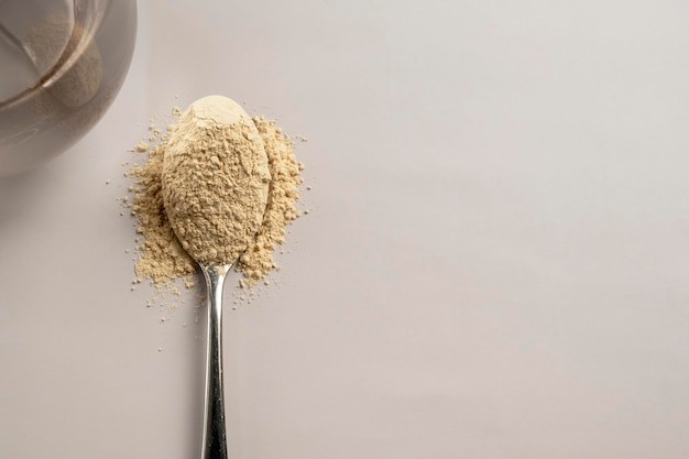 Heap of protein powder and a spoon with glass of water Food supplements