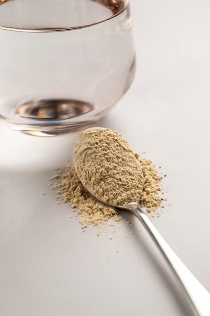 Heap of protein powder and a spoon with glass of water Food supplements