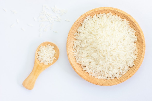 Heap of raw rice on wooden bowl and spoon