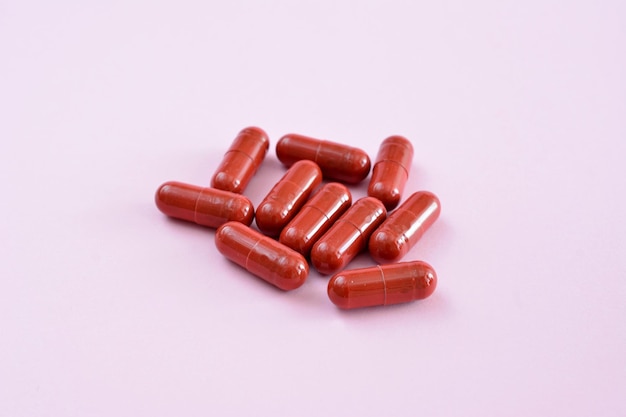 heap of red capsules on a pink background isolated closeup