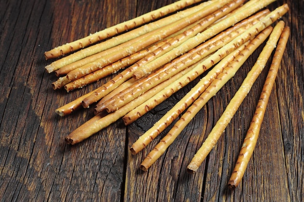 Heap salty bread sticks on dark wooden table