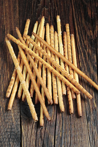 Heap salty breadsticks on dark wooden table