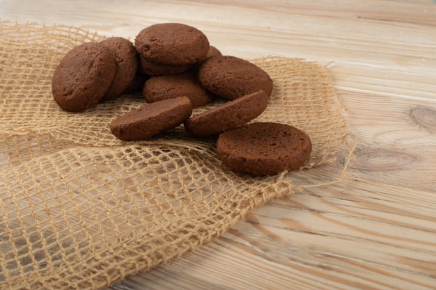 Heap of soft homemade chocolate butter cookie with chocolate filling on rustic table background. Brown round soft biscuits or small fresh round cocoa pies closeup