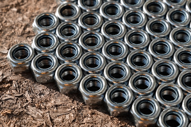 Heap of stainless screw-nuts on wooden background.