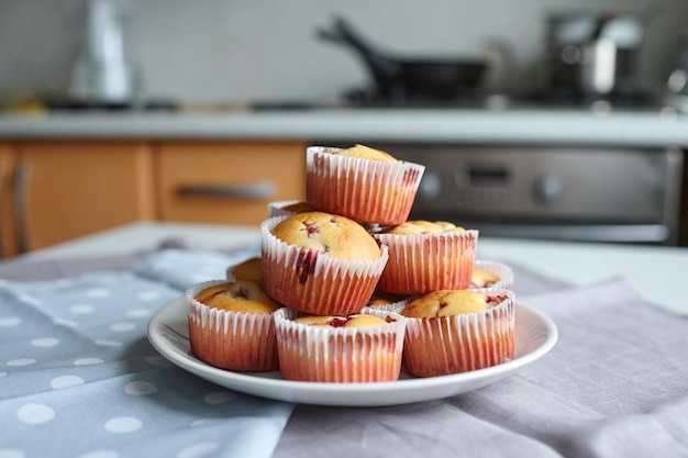 Heap of strawberry muffins on white plate over kitchen background