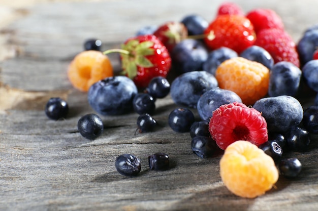 Heap of sweet tasty berries on wooden table close up