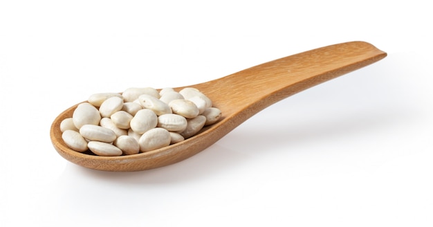 Heap of white beans in wood spoon on white wall