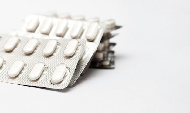 Heap of white medical pills in plastic package. Concept of healthcare and medicine.