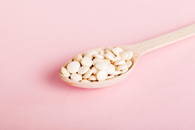 Heap of white pills on colored background Tablets scattered on a table Pile of red soft gelatin capsule Vitamins and dietary supplements concept