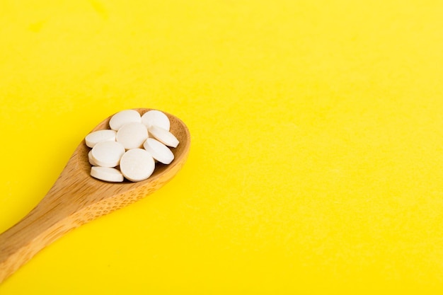 Heap of white pills on colored background Tablets scattered on a table Pile of red soft gelatin capsule Vitamins and dietary supplements concept