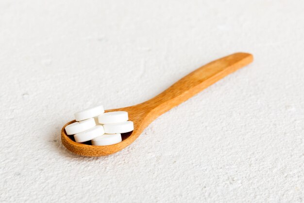 Heap of white pills on colored background Tablets scattered on a table Pile of red soft gelatin capsule Vitamins and dietary supplements concept