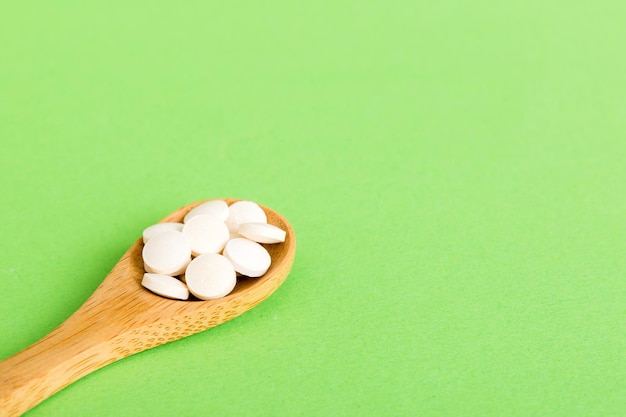 Heap of white pills on colored background Tablets scattered on a table Pile of red soft gelatin capsule Vitamins and dietary supplements concept