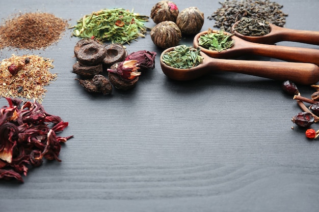 Heaps of different dry tea on grey wooden table space, closeup