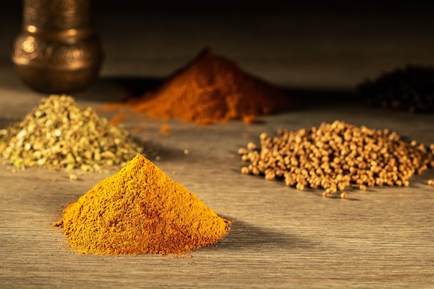 Heaps of different spices oregano black pepper curry on a wooden table lit by the morning sun