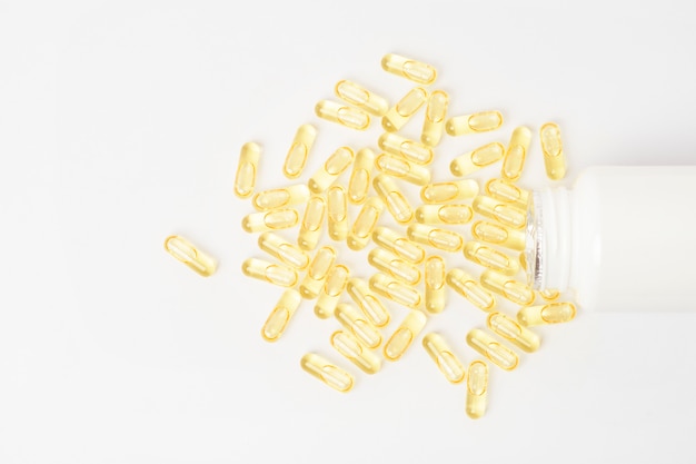 Heaps of yellow vitamins pills on white wall