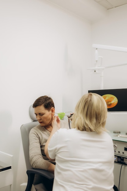 Hearing exam for elderly citizen people Otolaryngologist doctor checking mature womans ear using otoscope or auriscope at medical clinic