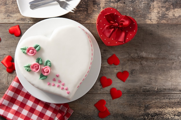 Heart cake for St. Valentine's Day,  decorated with roses and pink sugar hearts on wooden table