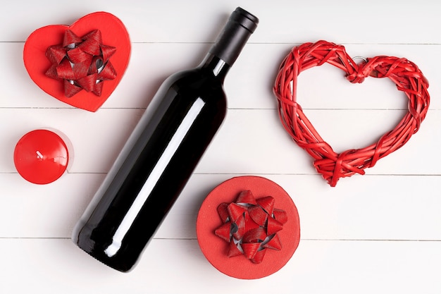 Heart, candle, wine bottle on white wooden surface. Valentine's day concept. Flat lay, top view, from above