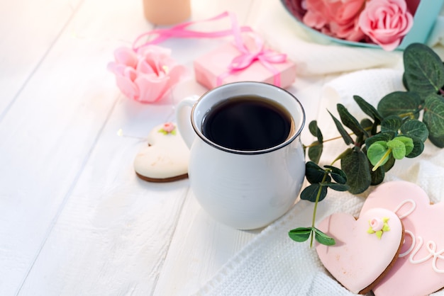 Heart cookies with cup of coffee on wooden background with plaid, copy space