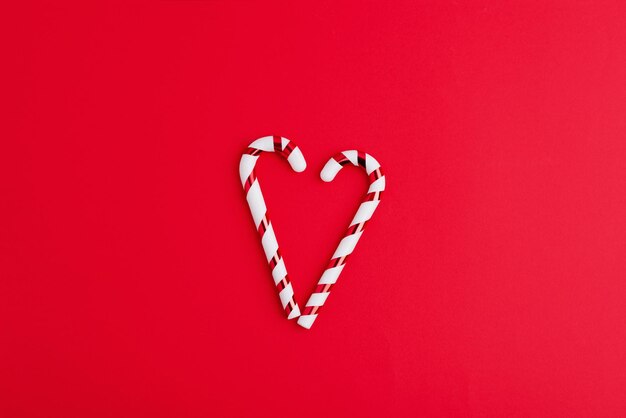 Heart from candy cane on a red background Creative minimal christmas art