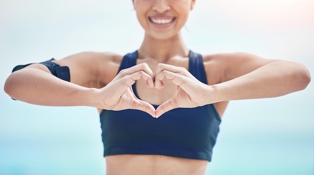 Heart hands and fitness of sports woman outdoor for freedom wellness and healthy review Closeup of happy athlete show finger shape for love support and motivation for care emoji sign and icon