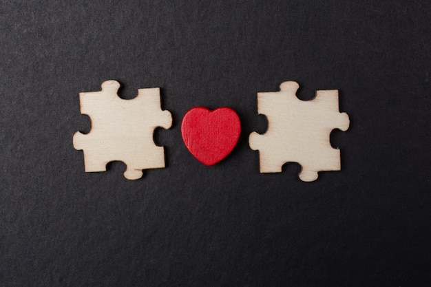 Heart icon between pieces of jigsaw puzzle as business strategy concept