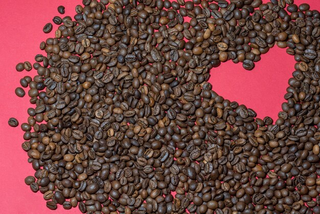 Heart laid out from coffee beans on a red background