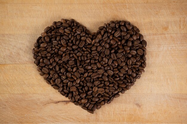 Heart made of coffee beans on wooden background