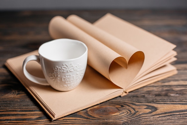 Heart made from book sheets with a cup, love and valentine concept on a wooden table