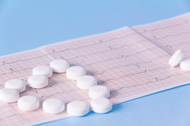 A heart made of large white drugs on an electrocardiogram of the heart on a blue background the conc