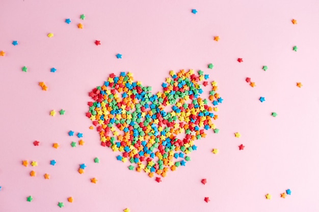 Heart made of multi-colored dots on pink surface