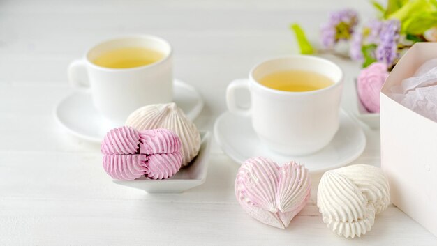 Heart shape marshmallows and cups with tea romantic composition Craft desert sweets with beverage