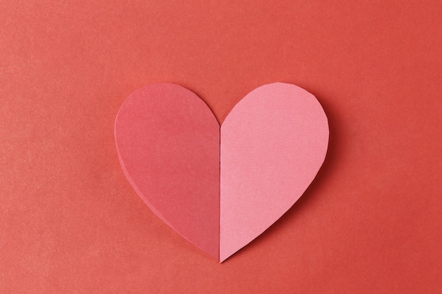 Heart shape of paper on the red cardboard background.