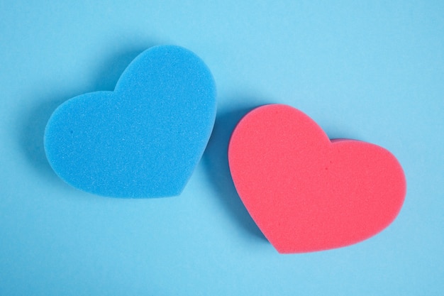 Heart shape sponges for shower on blue background copy space top view