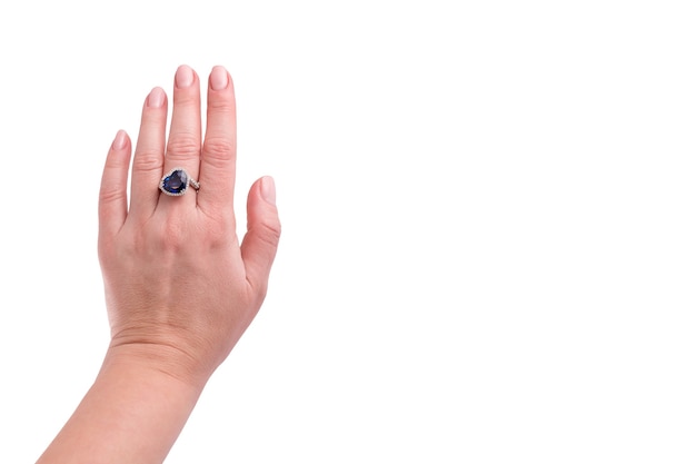 Heart shaped blue sapphire precious ring on woman hand isolated on white background.