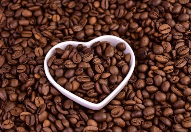 A heart shaped bowl of coffee beans with the word coffee in the middle