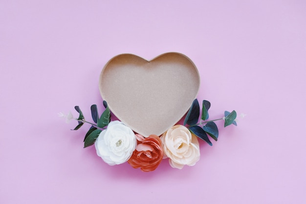 Heart shaped box  in a beautiful pink background with pretty flowers.