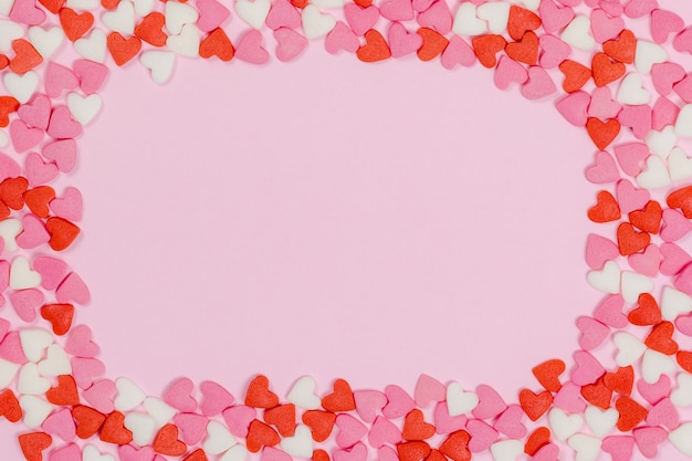 Heart shaped candies scattered on pink background love wedding concept