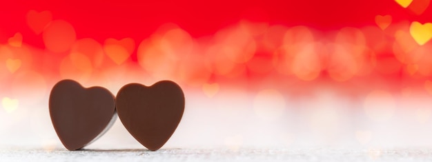 Heart shaped chocolates on red background with boke Happy Valentine's Day greeting card Banner