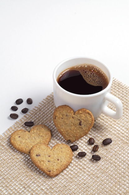 Heart-shaped cookies and a cup of coffee on white background