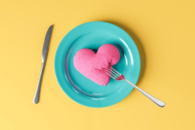 Heart shaped dessert with silverware served on yellow surface