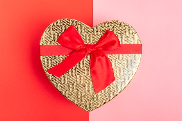 Photo heart shaped gift box with ribbon bow on pink, red background top view