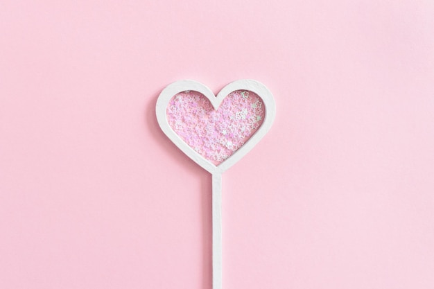 Heart shaped magic wand with star sequins on a pink pastel background