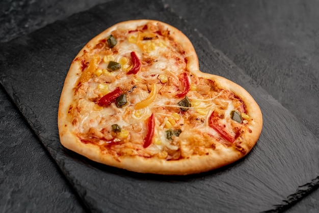 Heart-shaped pizza for Valentines Day on slate