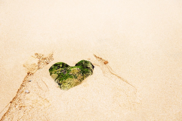 Photo heart-shaped stone on a sandy beach. beautiful nature background.