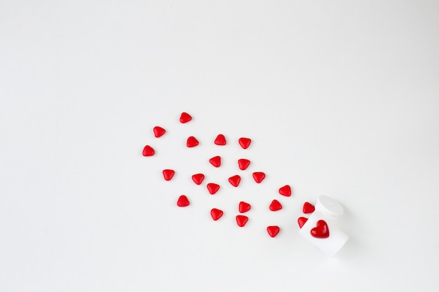 Heart shaped sweets fly from a white bottle