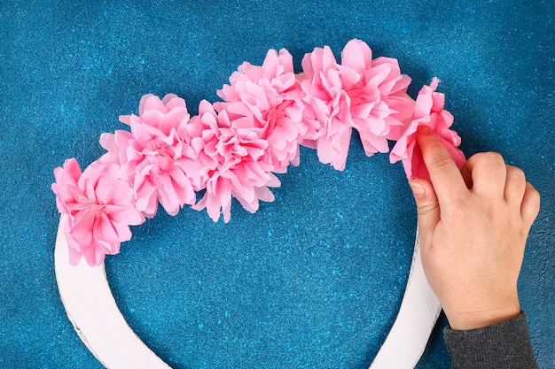 Heart shaped wreath decorated artificial flower made pink tissue paper napkins. 