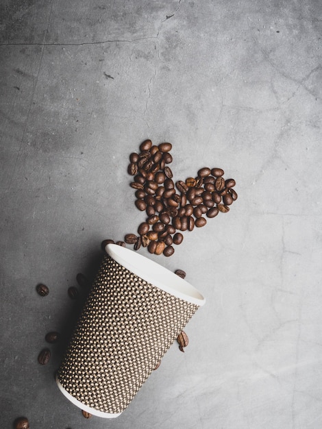 Heart symbol from coffee beans from a disposable paper cup