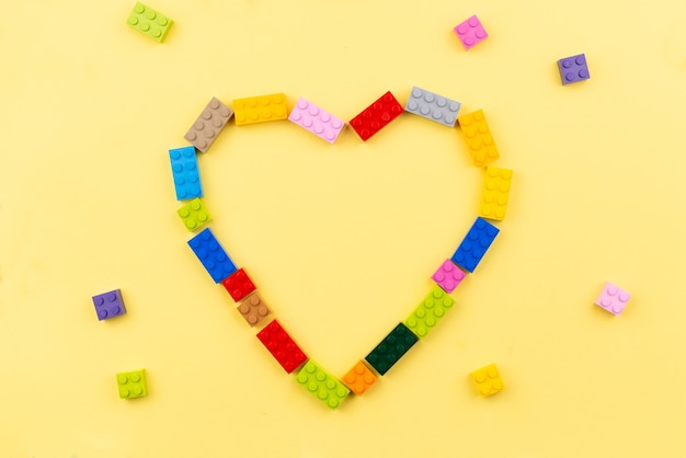 Heart of Toy Colored Plastic Building Blocks on Yellow Background