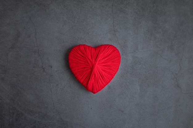 A heart for Valentine s Day made of red wool threads on a dark background Concept holidays love